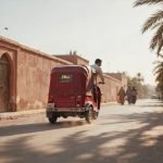 A tuk tuk Marrakech ride passing through a palm-lined street in the Red City at golden hour