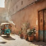 A colourful tuk tuk driving through a Marrakech street during golden hour - Tuk Tuk Marrakech