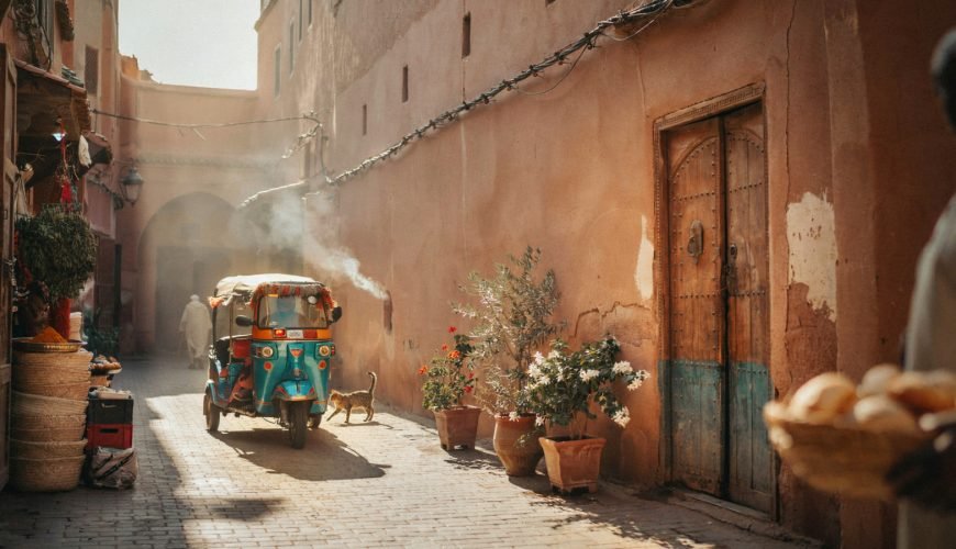 A colourful tuk tuk driving through a Marrakech street during golden hour - Tuk Tuk Marrakech
