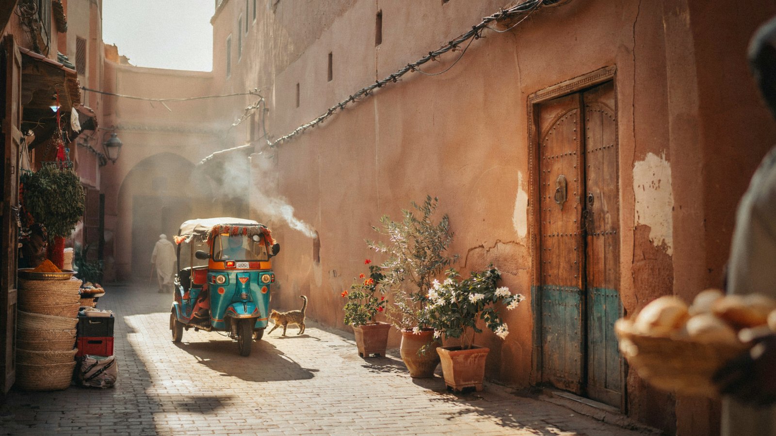 A colourful tuk tuk driving through a Marrakech street during golden hour - Tuk Tuk Marrakech